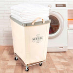 Corner Heavy-Duty Canvas Hamper w/Wheels, 24"W x 17.7"D, Natural White | Space-saving corner design holds 3 to 4 loads of laundry with a durable steel frame, smooth-rolling locking wheels